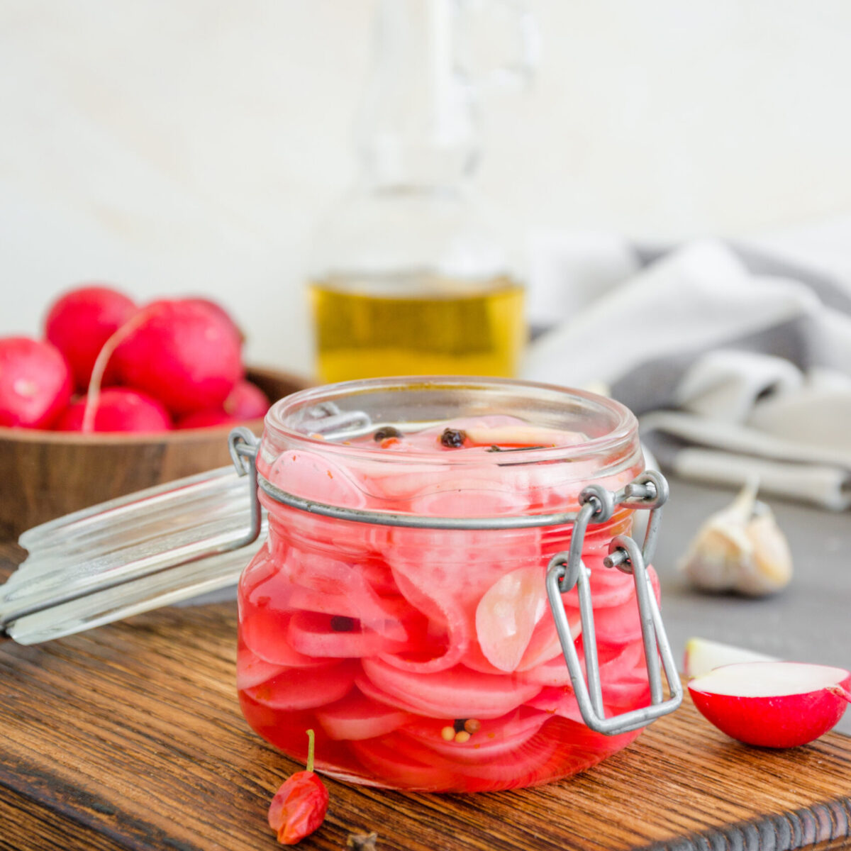 Fermented food. Marinated radish with onion, garlic and spices in a jar on a cutting board on a dark concrete background. Vertical orientation. Copy space Fermented food. Marinated radish with onion, garlic and spices in a jar on a cutting board on a dark concrete background. Vertical orientation. Copy space.