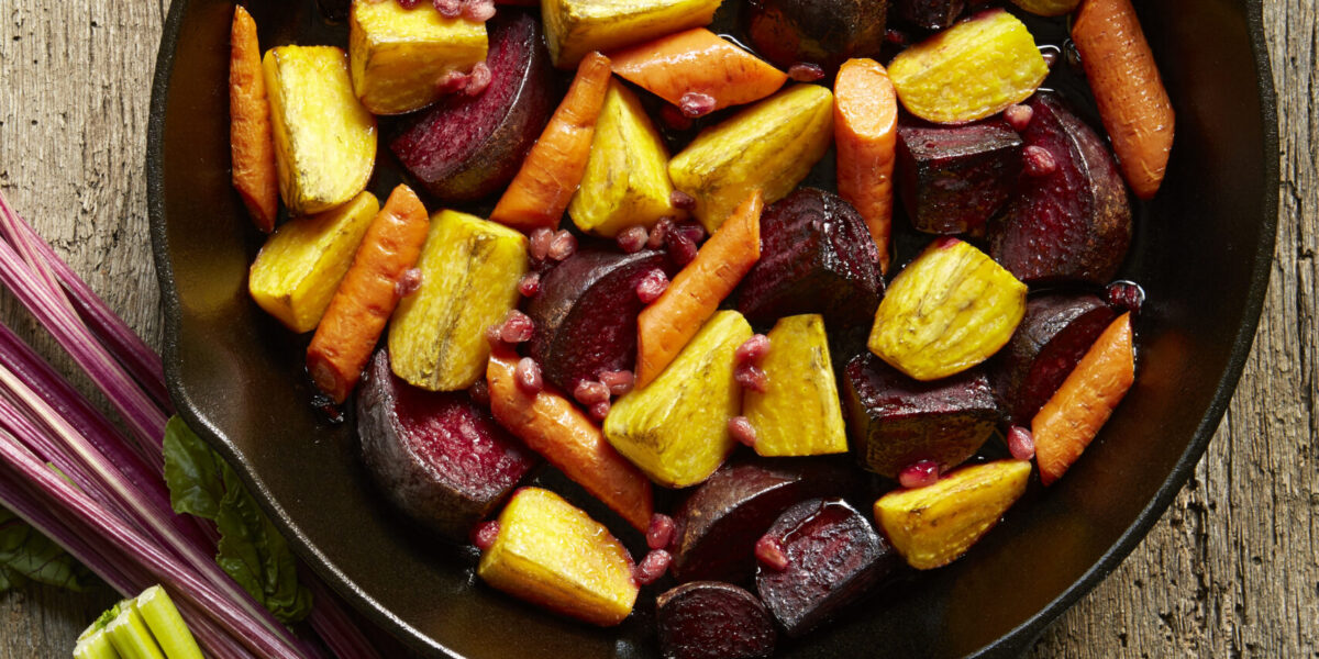 Still life of roasted golden and red beets with carrots in pan