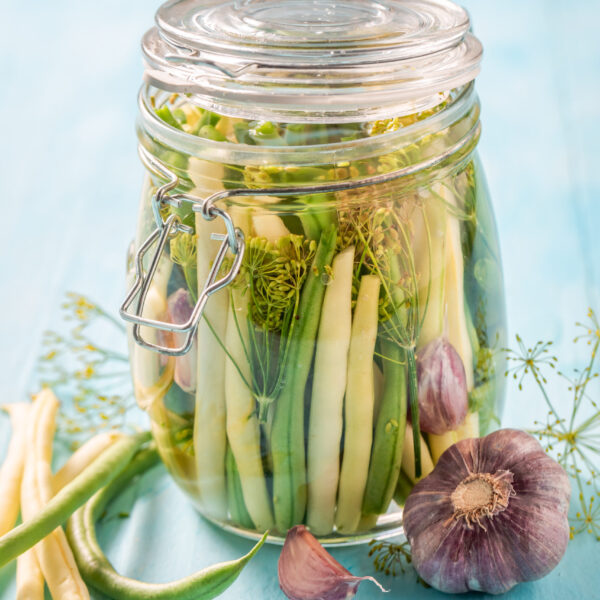 Homemade pickled green and yellow beans on blue table
